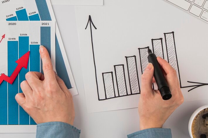 Top view of office desk with growth chart and hands