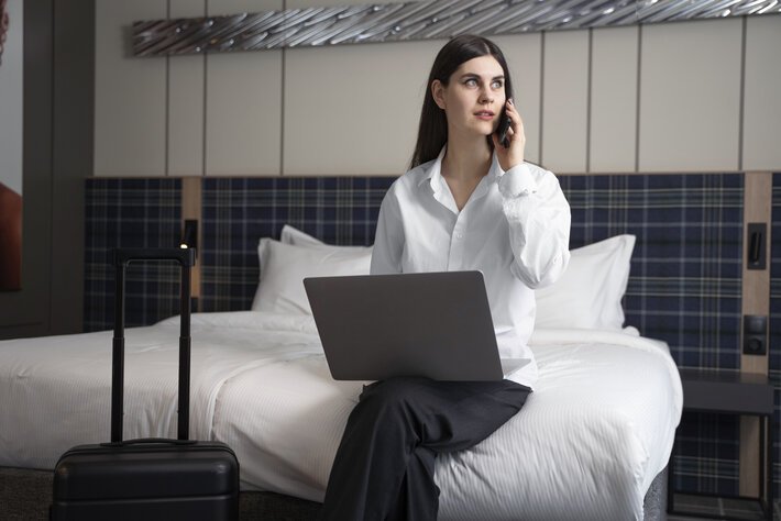 Young woman talking on her smartphone in a hotel room